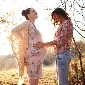 Lesbians holding pregnant stomach.